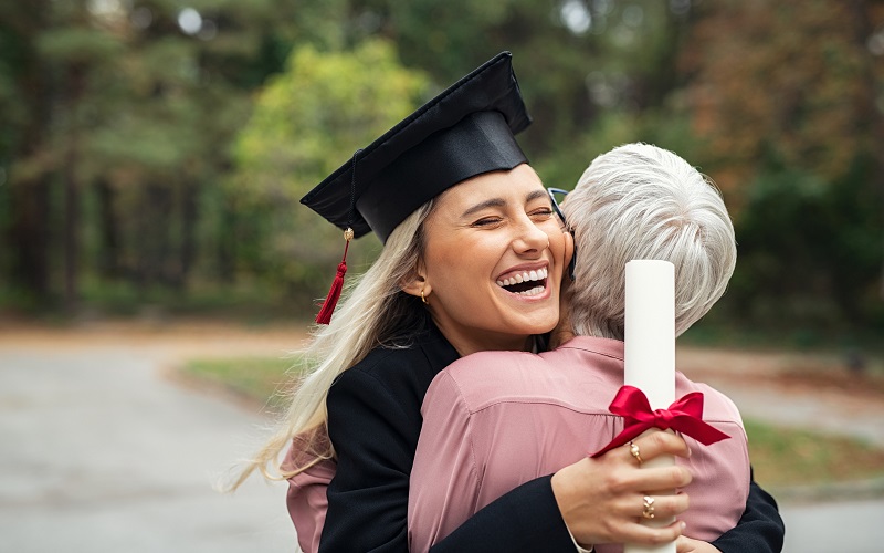zadowolona absolwentka z dyplomem przytula mamę