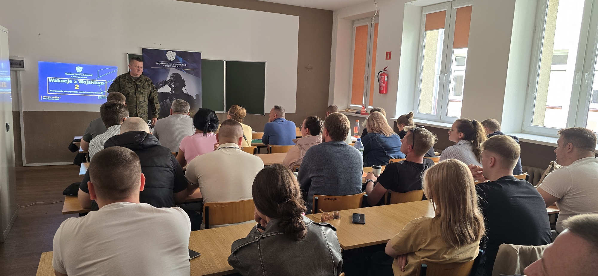 Żołnierz opowiadający grupie studentów przy ławkach