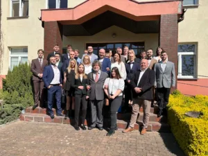 Zdjęcie grupowe ubranych na galowo absolwentów Logistyki kutnowskiej uczelni